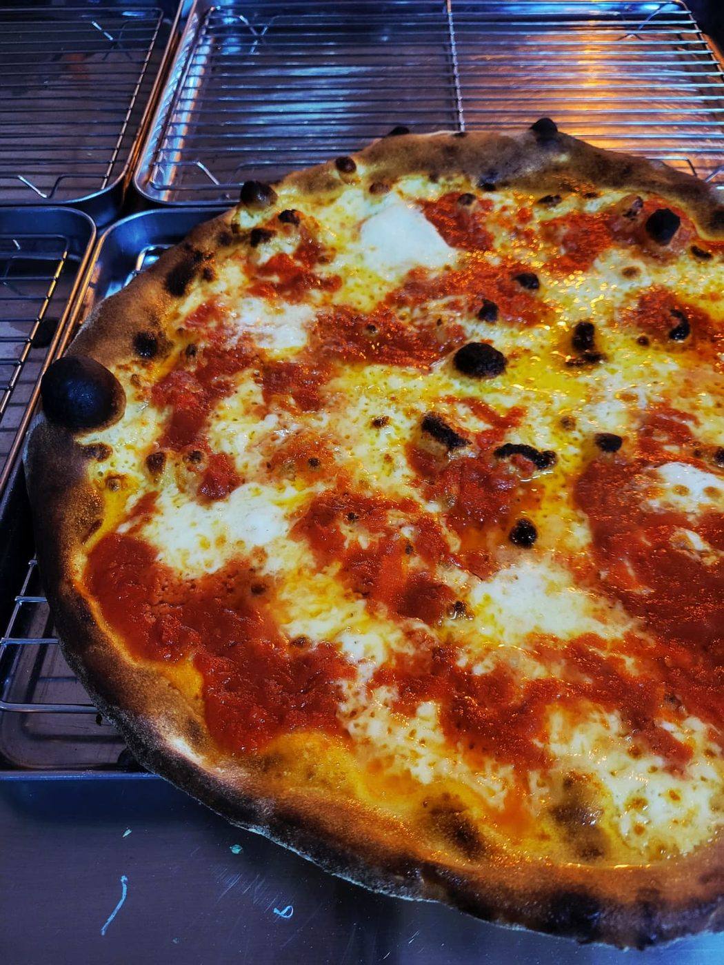 A New York style pizza on a steel tray